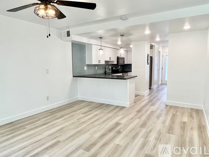 A spacious kitchen with a ceiling fan and pendant lights.