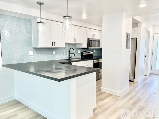 A kitchen with a black countertop and white cabinets.