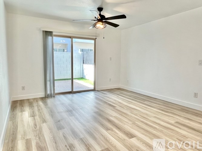 A spacious room with a ceiling fan and sliding glass doors leading to a balcony.