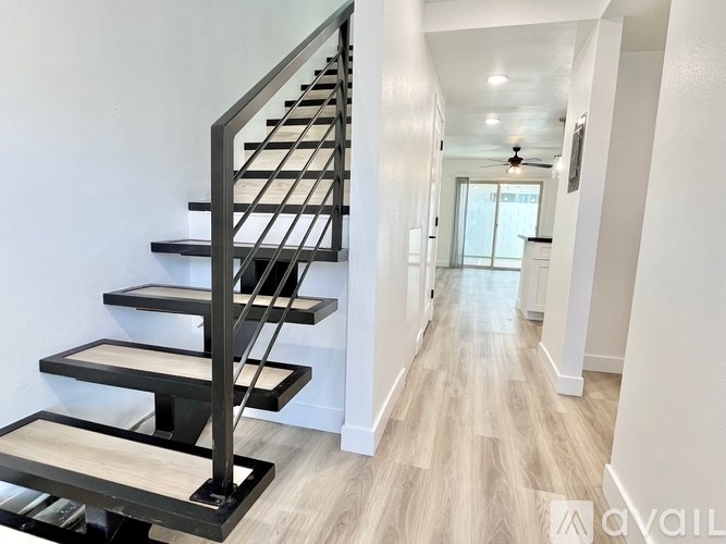 A modern staircase with a metal railing and wooden steps.