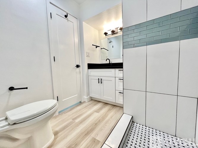 A white toilet in a bathroom with a white cabinet and a mirror.