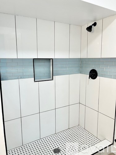 A shower with a black drain and a black and white tile floor.