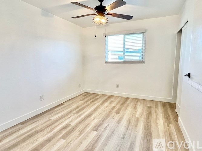 A room with a ceiling fan and a window with blinds.