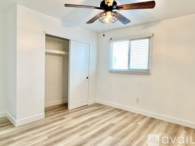 A room with a ceiling fan and a window with blinds.