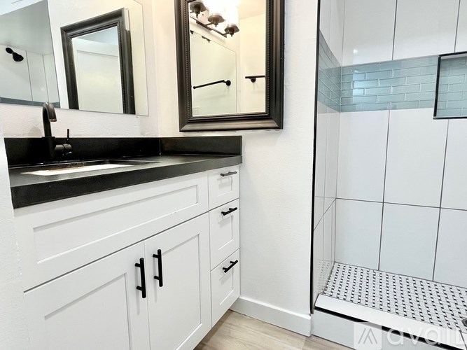 A bathroom with a black countertop and white cabinets.