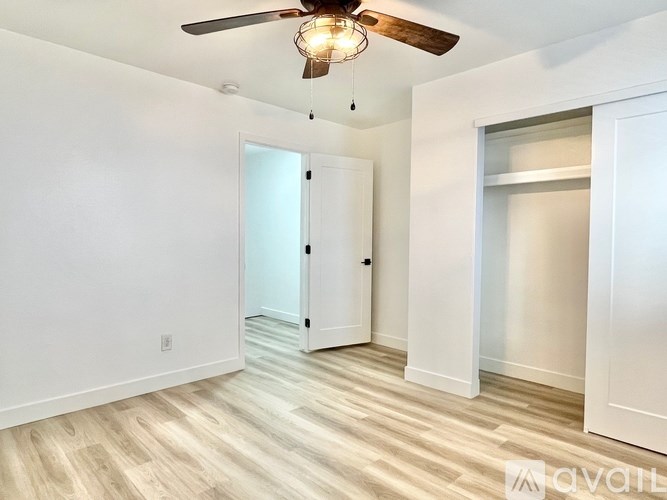 A room with a ceiling fan and a door leading to another room.