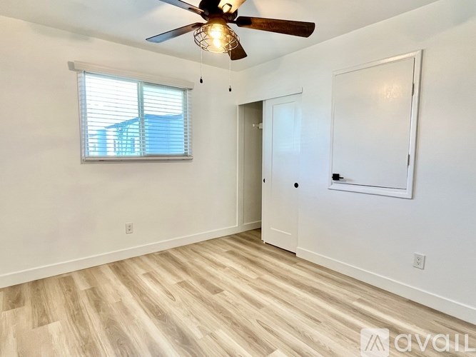A room with a ceiling fan and a window with blinds.
