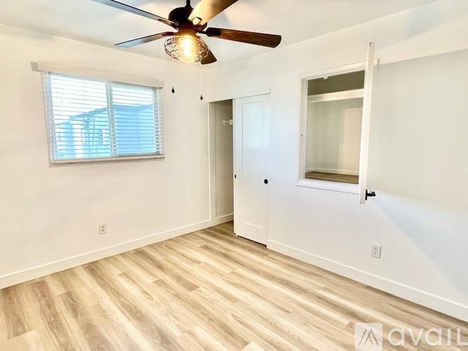 A room with a ceiling fan and a window with blinds.