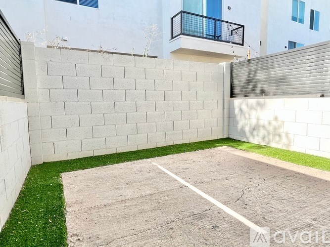 A backyard with a white wall and a green lawn.
