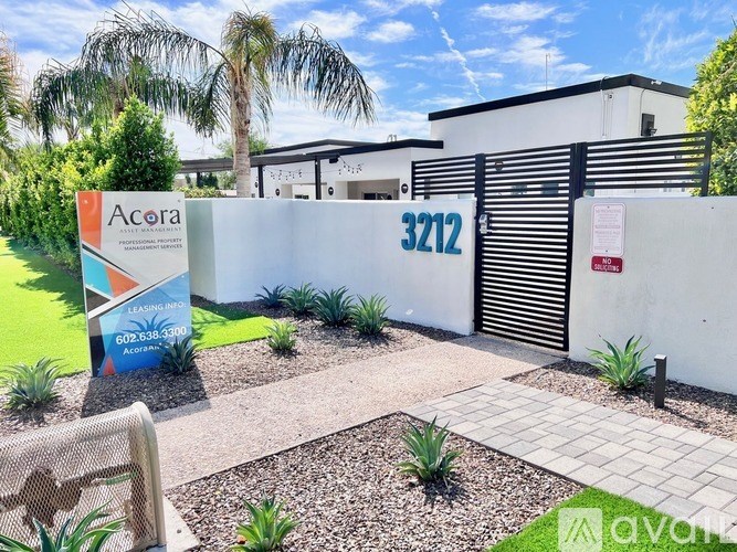 The image shows a well-maintained garden in front of a building with a sign that reads "Acora".