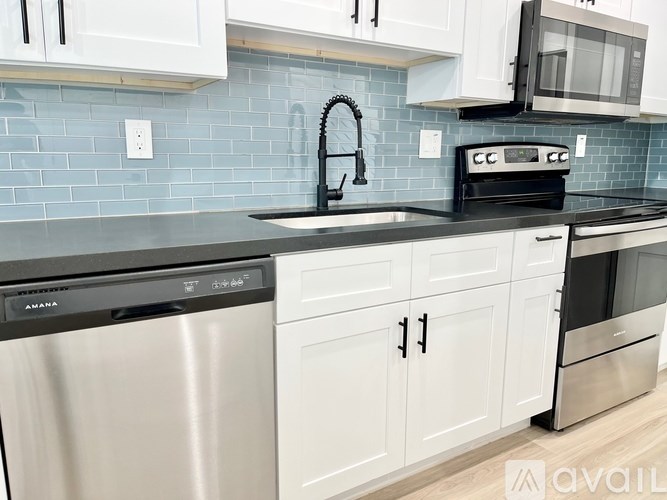 A kitchen with a stainless steel dishwasher and white cabinets.
