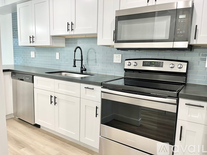 A modern kitchen with white cabinets and stainless steel appliances.
