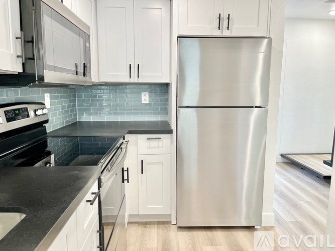 A kitchen with a stainless steel refrigerator and white cabinets.