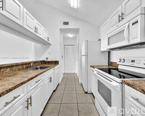 A kitchen with white appliances and cabinets.