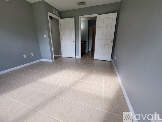 A room with tile flooring and two white doors.