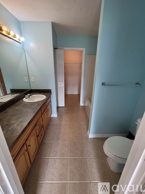 A bathroom with a toilet, sink, and mirror.