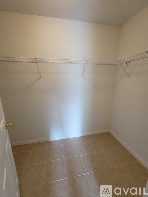 A white closet with a white door and a white shelf.