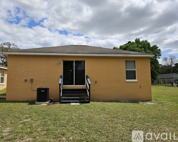 A yellow house with a black air conditioner unit in front.