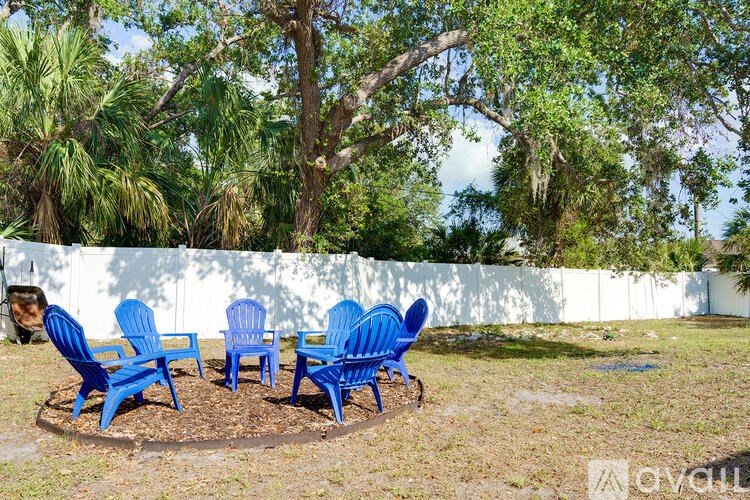 Four blue chairs are arranged in a circle on a patch of dirt.