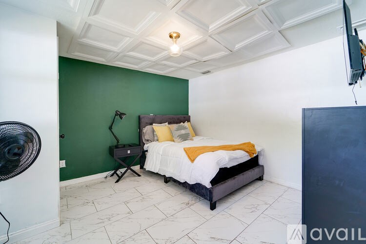 A bedroom with a bed, a fan, and a television.