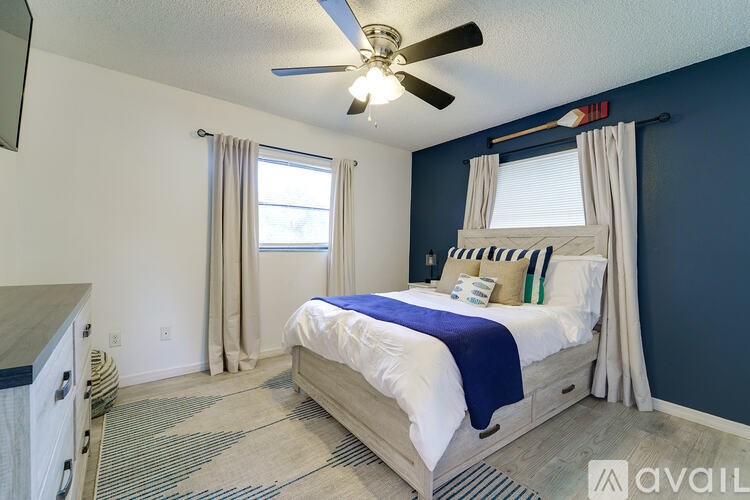 A bedroom with a bed, a ceiling fan, and a window with curtains.