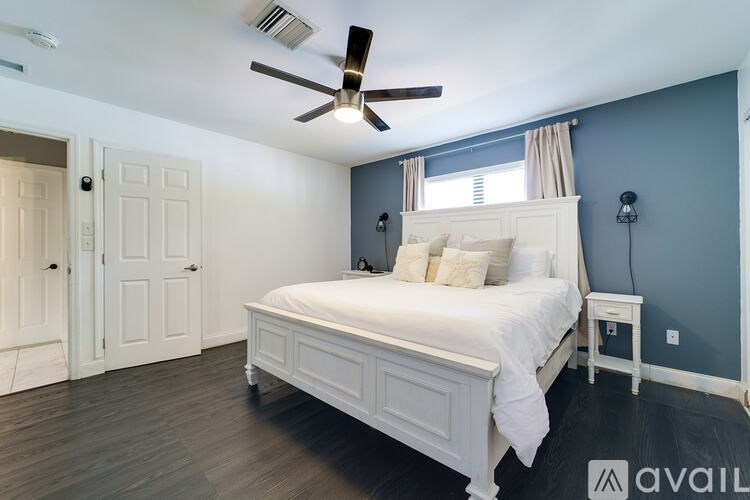 A bedroom with a white bed and a ceiling fan.