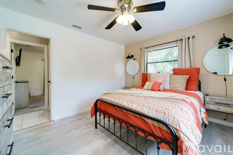A bedroom with a bed, dresser, mirror, and a window with curtains.