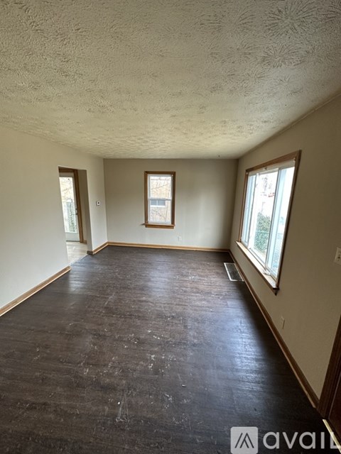 A room with wooden floors and two windows.