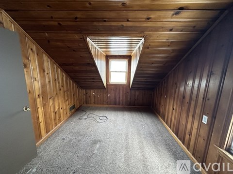 A room with wooden walls and a carpeted floor with a window.