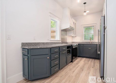 A kitchen with dark grey cabinets and a granite countertop.