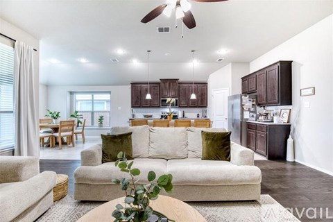 A living room with a couch, chairs, and a table with a plant on it.