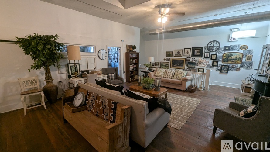 A living room with a couch, a chair, a table, and a potted plant.