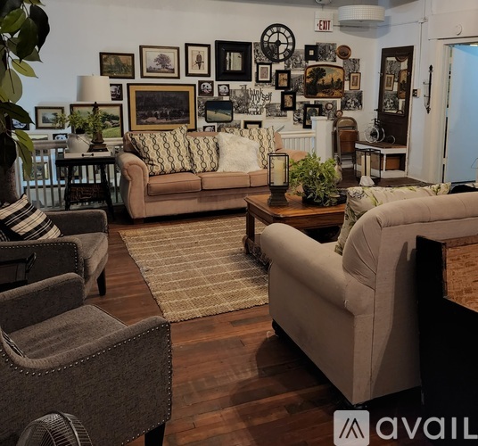 A living room with a couch, chair, and a table with a lamp on it.