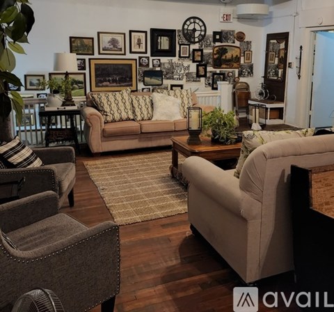 A living room with a couch, chair, and a table with a lamp on it.