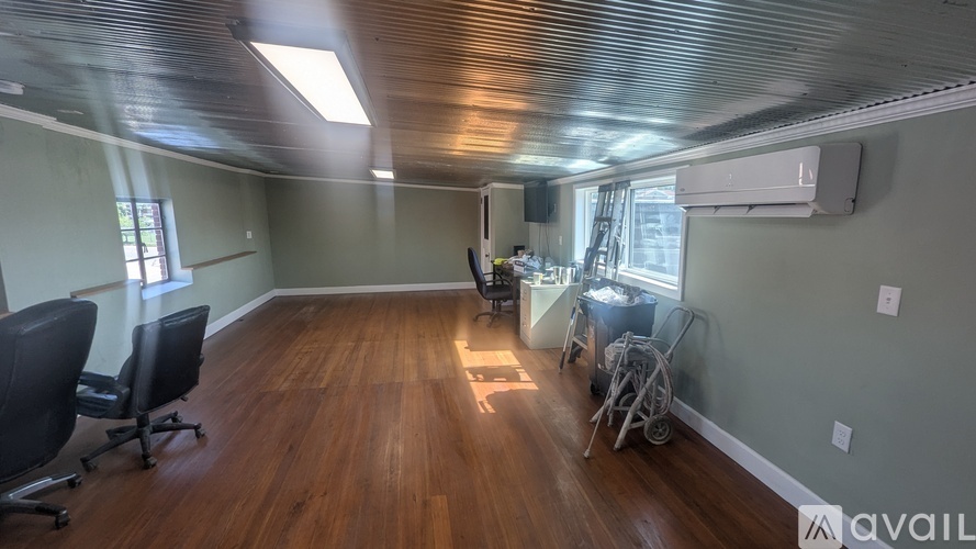 A room with wooden floors and a person working on a computer.