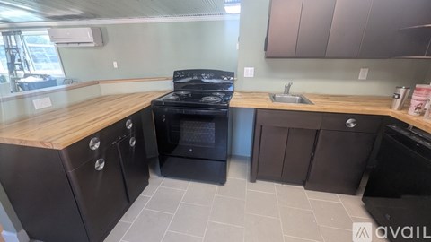 A kitchen with a black stove top oven and black dishwasher.