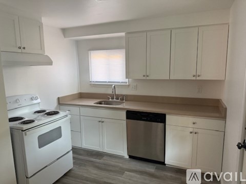 A kitchen with white cabinets and a stove top oven.