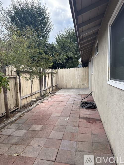 A patio with a red tile floor and a wooden fence.