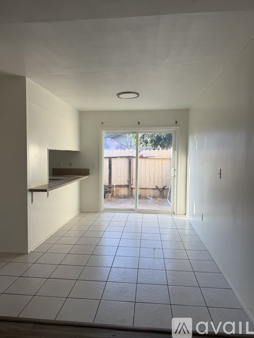 A white tiled room with a sliding glass door leading outside.