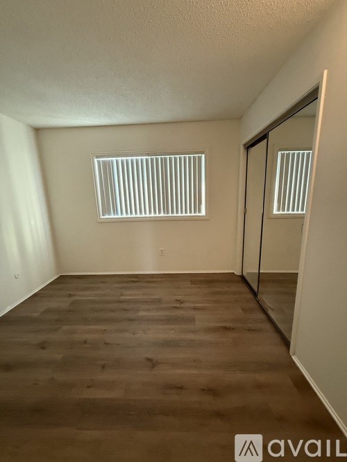 A room with wooden flooring and a window with blinds.