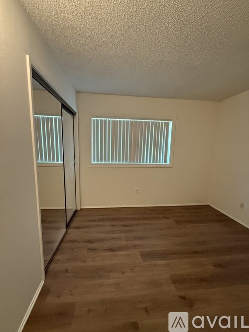 A room with wooden flooring and a window with blinds.