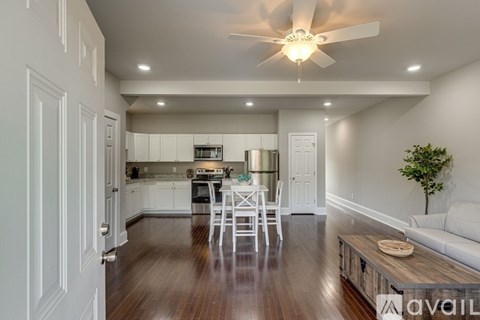 A modern kitchen with white cabinets and a wooden floor.