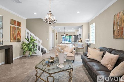 A living room with a black couch and a glass coffee table.