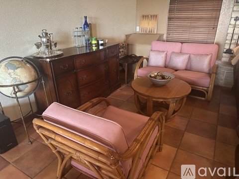A living room with a pink couch and wooden chairs.