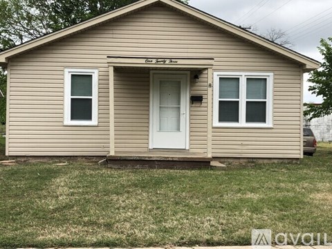 A small house with a brown siding and a white door.