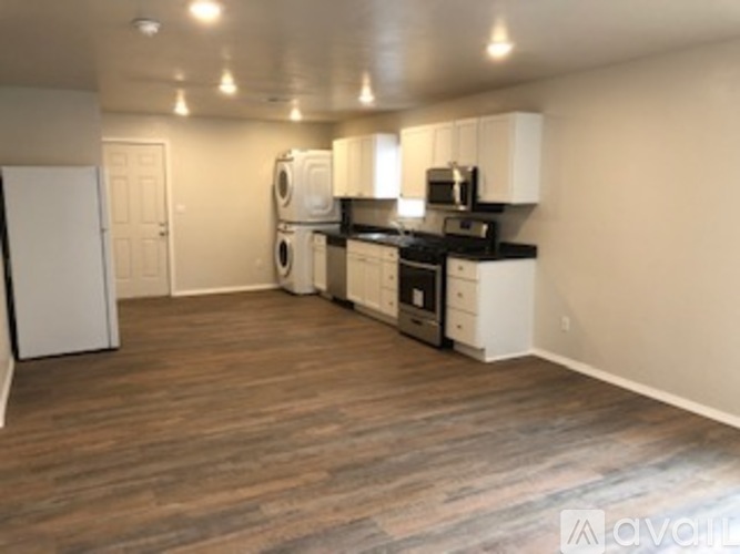 A kitchen with white cabinets and a wooden floor.