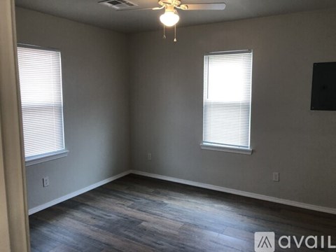 A room with a ceiling fan and two windows.