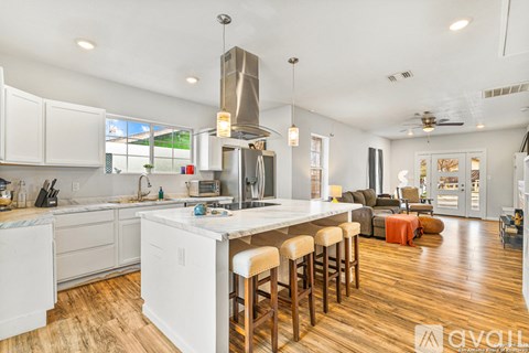 A kitchen with white cabinets and a large island with bar stools.