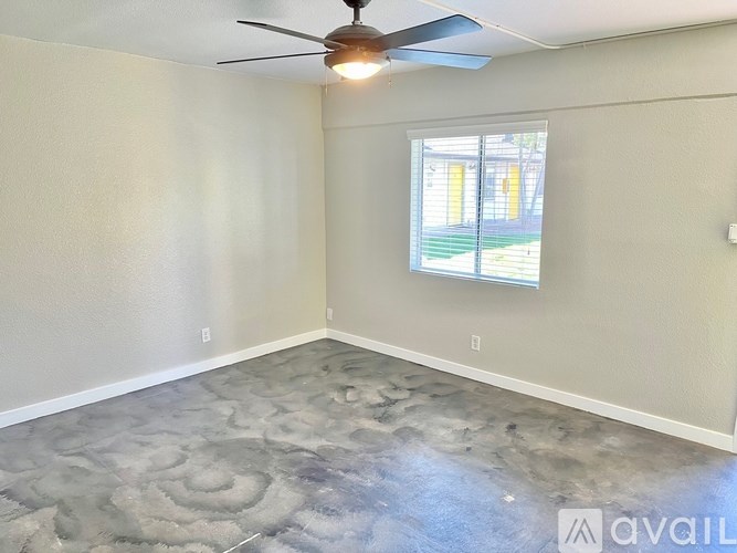 A room with a ceiling fan and a window with a view of a green lawn.