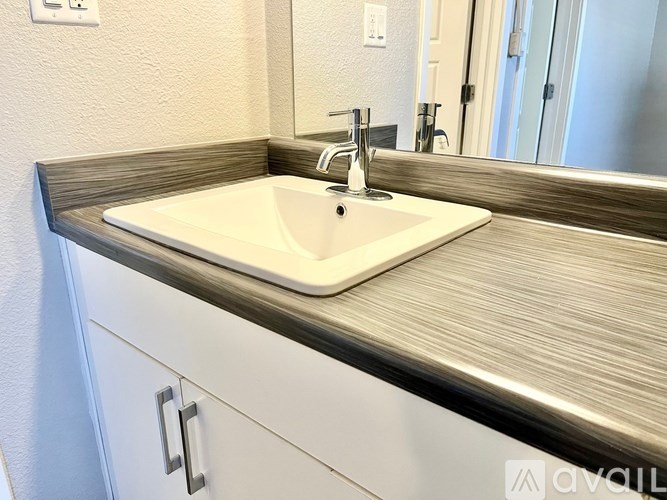 A white sink with a silver faucet is installed in a countertop.